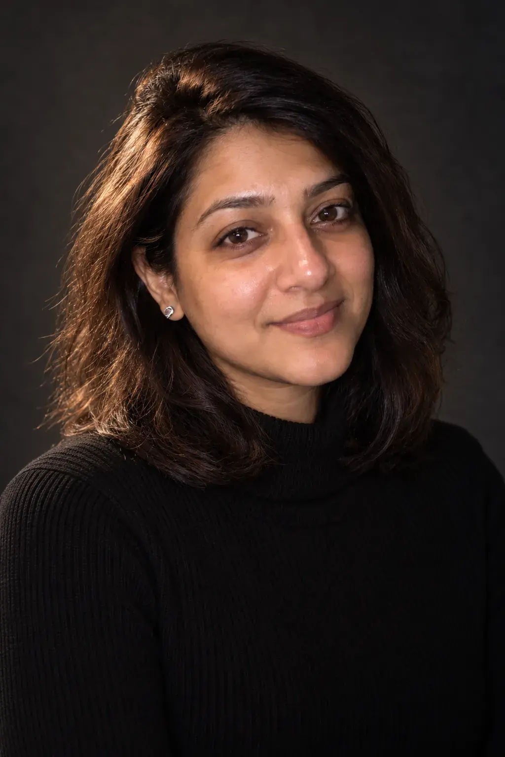 The same woman in a black sweater, a dark studio portrait