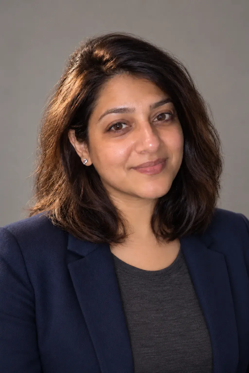 The same woman in a navy blazer, a professional headshot